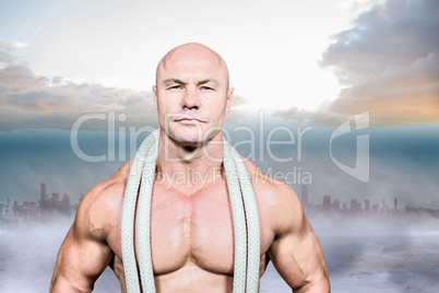 Composite image of portrait of confident fit man with rope aroun