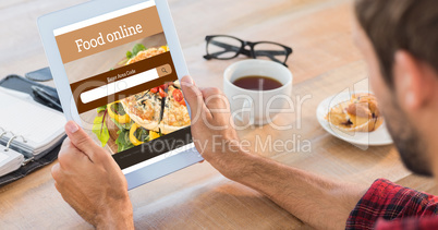 Composite image of rear view of man using tablet on wooden table