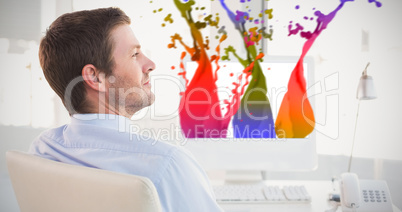 Composite image of smiling businessman sitting at his desk