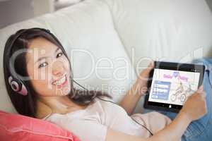 Composite image of girl using her tablet pc on the sofa and list