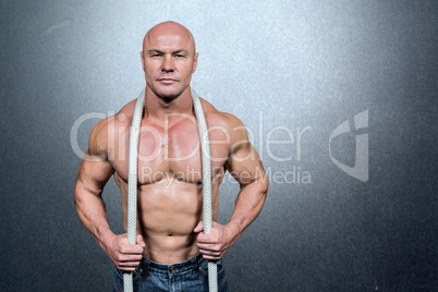 Composite image of portrait of healthy man holding rope