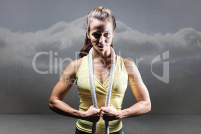 Composite image of portrait of healthy woman holding rope around