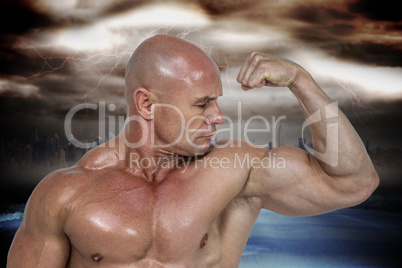 Composite image of muscular man looking at bicep