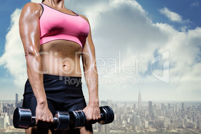 Composite image of low angle view of woman exercising with dumbb