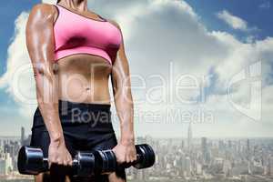 Composite image of low angle view of woman exercising with dumbb