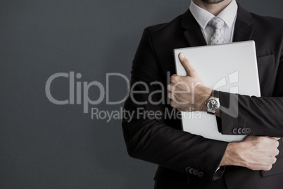 Composite image of mid section of businessman holding computer