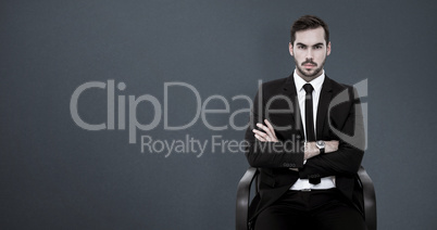 Composite image of serious businessman sitting with arms crossed