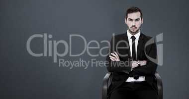 Composite image of serious businessman sitting with arms crossed