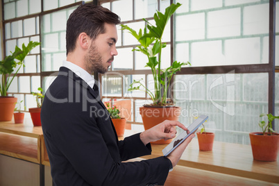 Composite image of concentrated businessman touching his tablet