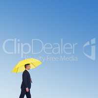 Composite image of businessman with yellow umbrella walking on w
