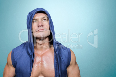 Composite image of muscular man in blue hood looking up