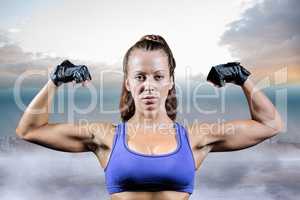 Composite image of portrait of woman with gloves flexing muscles