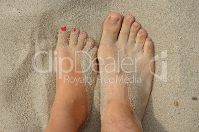 feet of father and his teen daughter on the sand