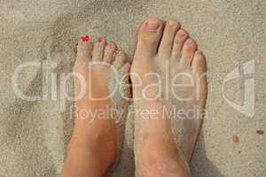 feet of father and his teen daughter on the sand