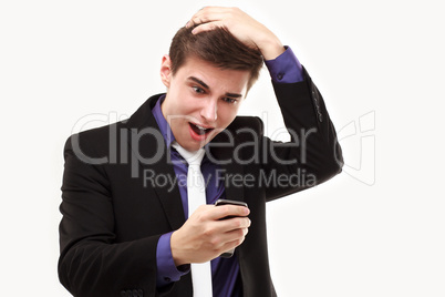 Young businessman amazedly looking at the phone holding on to th