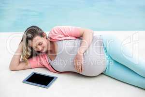 Pregnant woman relaxing outside using tablet