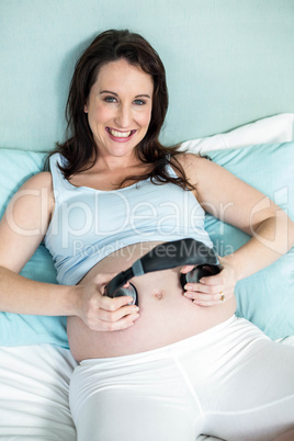 Pregnant woman putting headphones on her belly