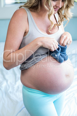 Pregnant woman with knitted slippers on her belly