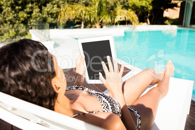 Fit brunette lying on deck chair and using tablet