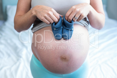 Pregnant woman with knitted slippers on her belly