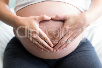 Pregnant woman doing a heart with her hand on her belly