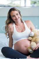 Pregnant woman sitting with a teddy bear