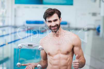 Fit man holding a weighting scale with thumbs up