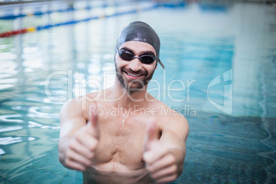 Smiling man wearing swim cap and goggles with thumbs up