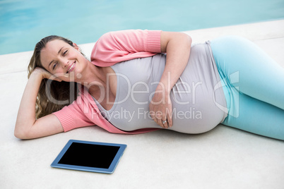 Pregnant woman relaxing outside using tablet