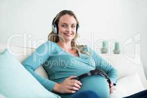 Pregnant woman listening to music with headphones on belly