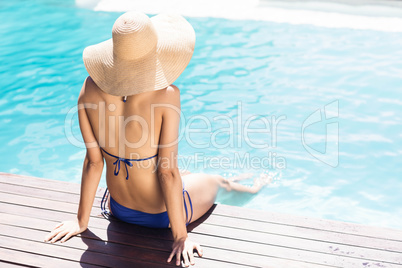 Woman with hat sitting on pools edge