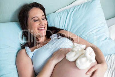 Pregnant woman with baby shoes on belly