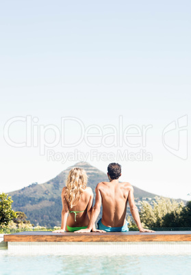 Rear view of couple sitting bu the pool
