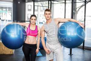 Fit couple posing with sport ball
