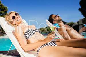 Peaceful couple sunbathing and holding cocktails