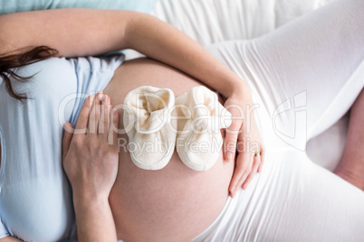 Pregnant woman with baby shoes on belly