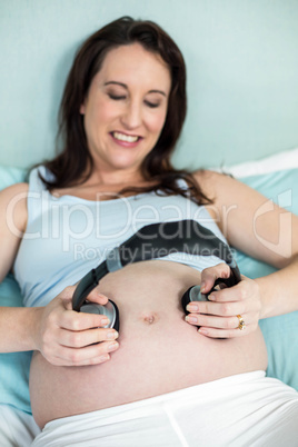 Pregnant woman putting headphones on her belly