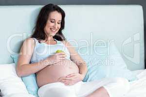 Pregnant woman holding an apple on her belly