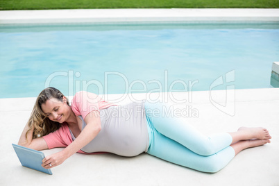 Pregnant woman relaxing outside using tablet