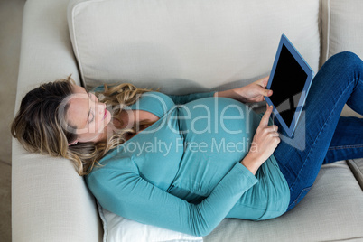 Pregnant woman using tablet lying on the couch