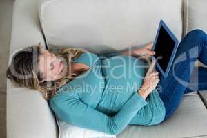 Pregnant woman using tablet lying on the couch