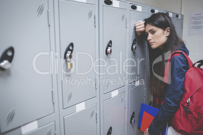 Sad student leaning on locker