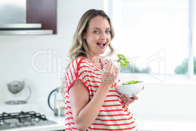 Pregnant woman eating a bowl of salad