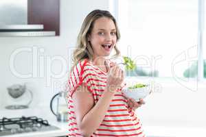 Pregnant woman eating a bowl of salad