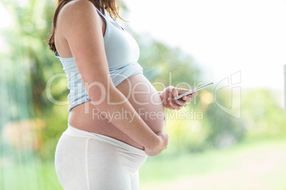 Pregnant woman touching her belly and texting