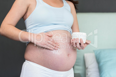 Pregnant woman applying cream to her belly