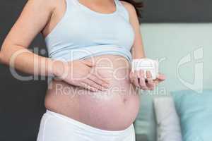 Pregnant woman applying cream to her belly
