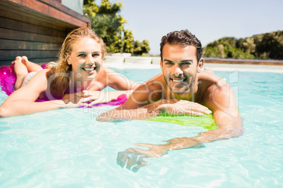 Happy couple with lilos in the pool