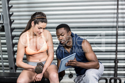 Athletic woman and trainer looking at tablet