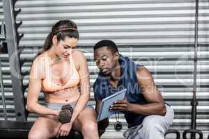 Athletic woman and trainer looking at tablet